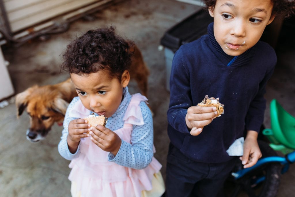 Sister and Brother eat s'mores standing next to each other at their Brooklyn family photo session. 