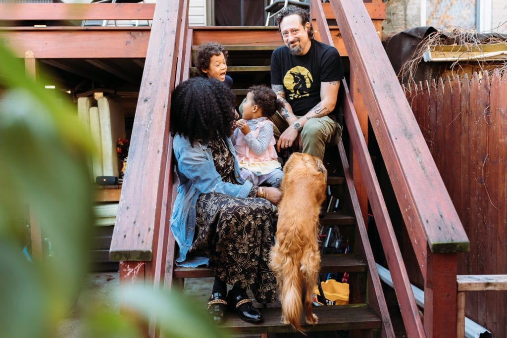 Brother and sister tease each other while Mom looks on and Dad looks at the camera on the stairs of their Bed Stuy Brooklyn family photo session. 