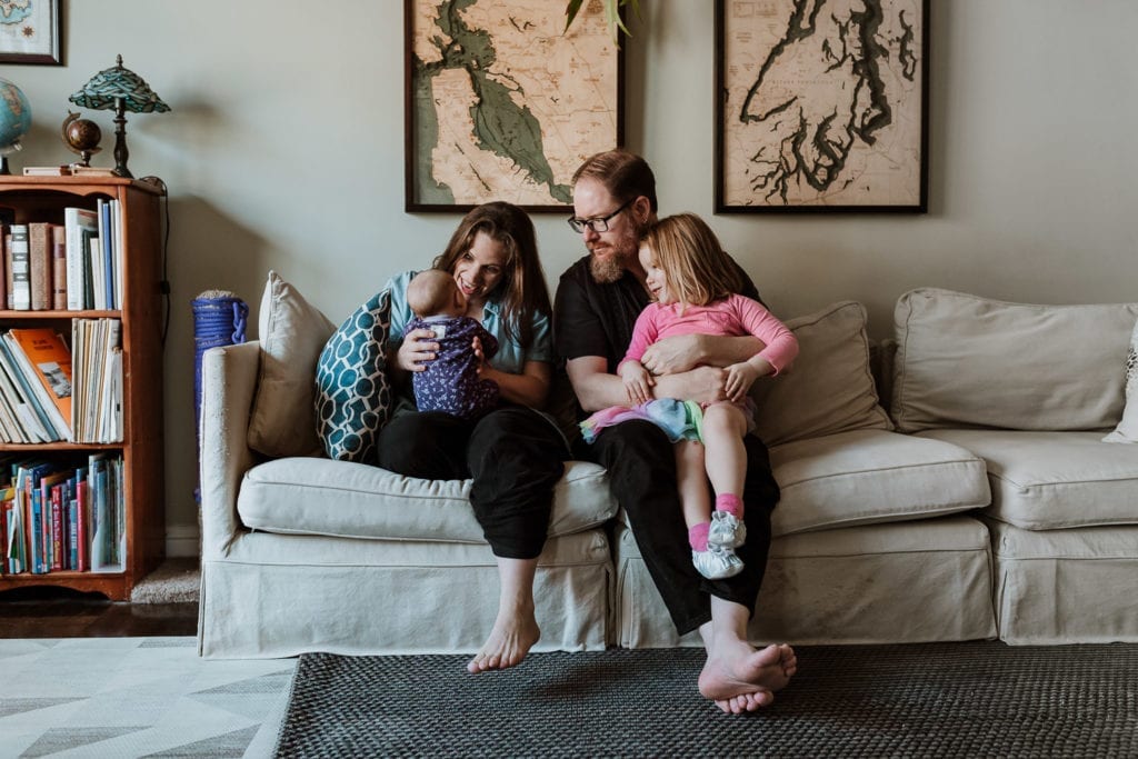 NYC newborn photography with a family on the couch staring at their newborn. 