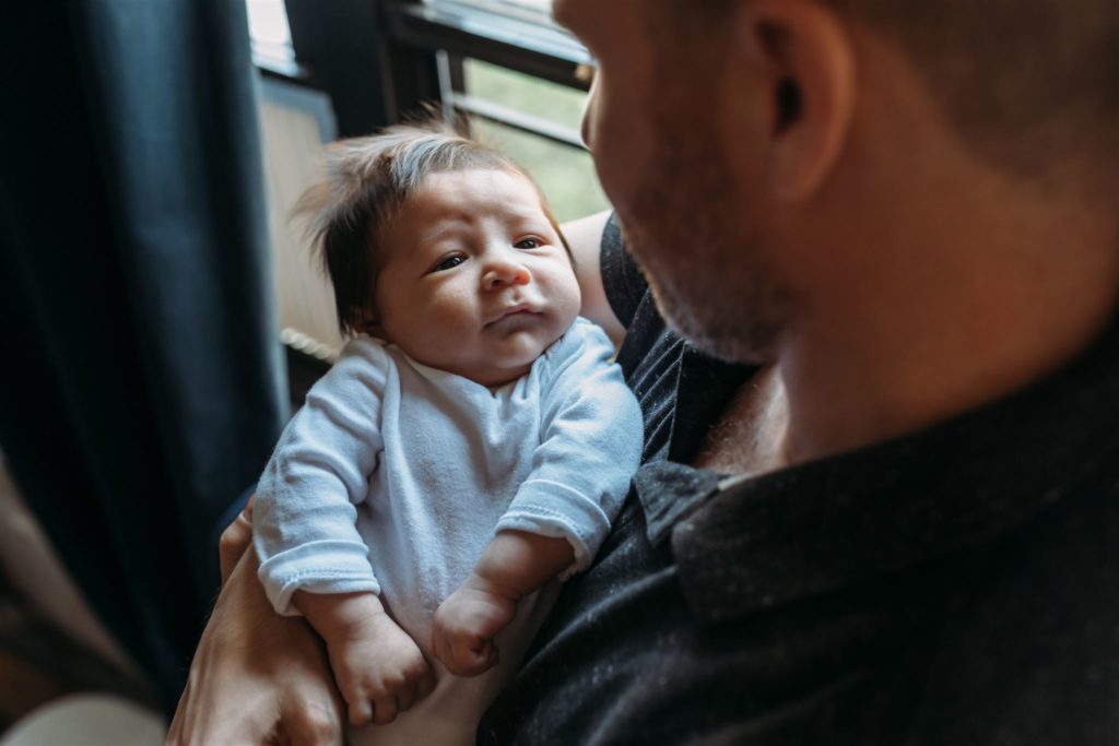 Father and newborn gaze each other in home photo shoot in NYC