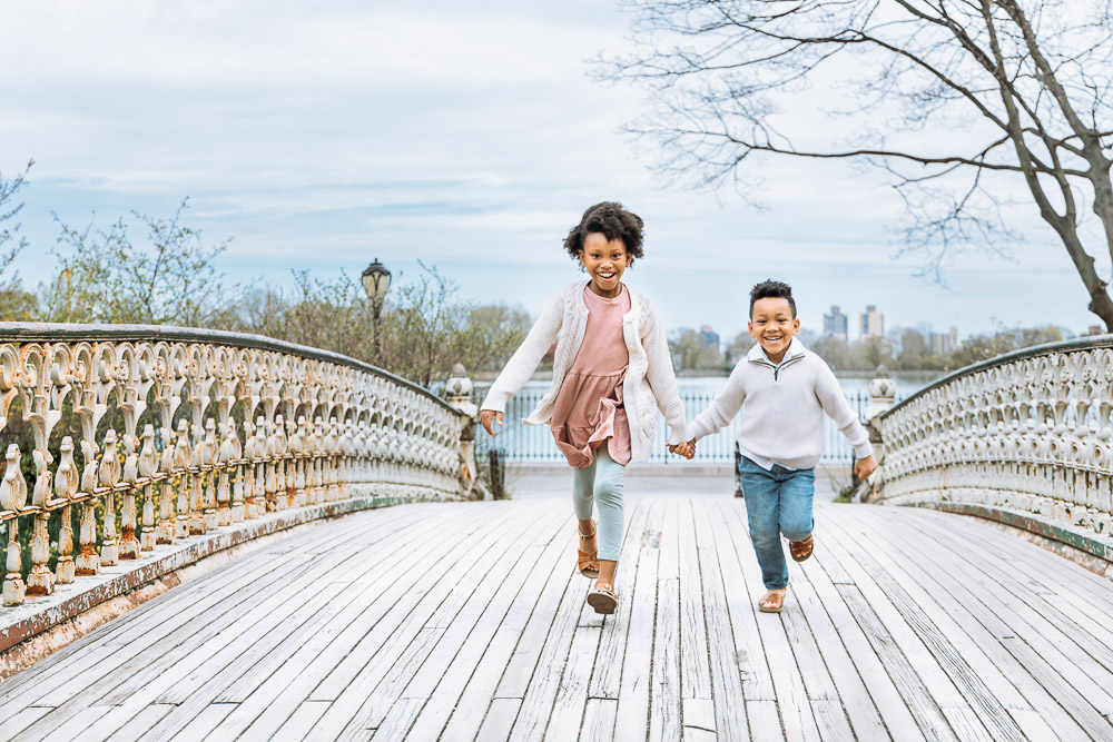 Brother and sister running through a bridge in Westchester County NY