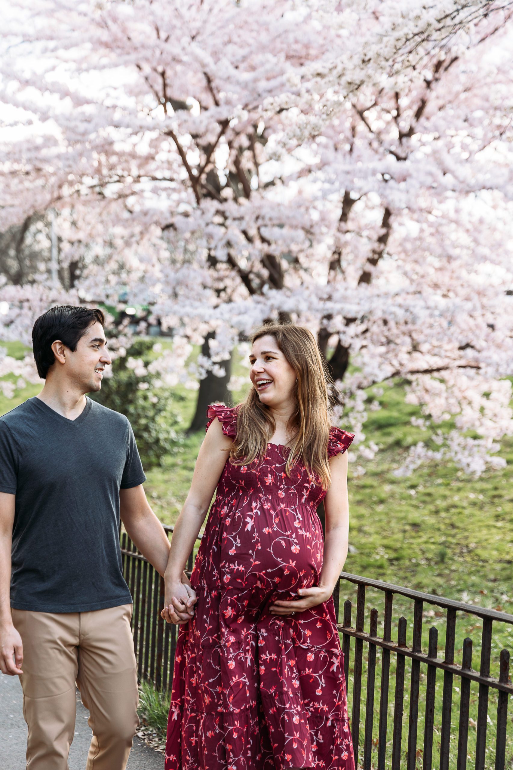 Adorable husband and wife couple pose outside of their New York City home for their maternity photos and celebrating her growing baby bump and her natural pregnancy glow